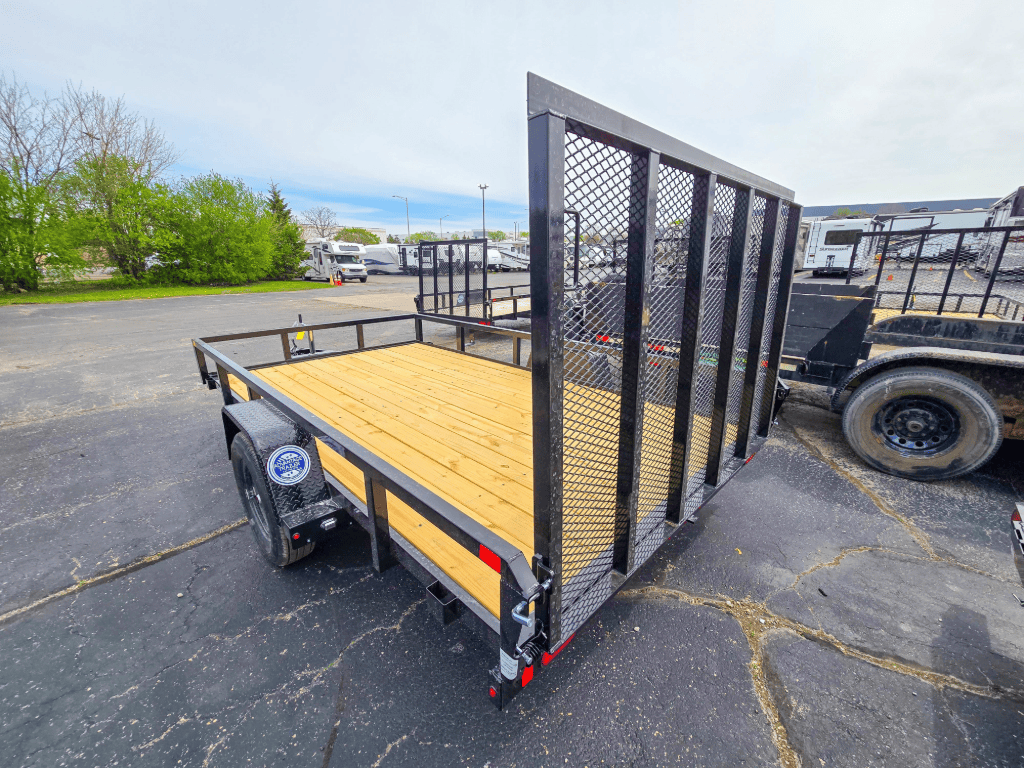 Sure-Trac Tube Top single-axle utility trailer with a wooden deck and rear mesh ramp gate, ideal for hauling needs and utility trailers in Illinois.